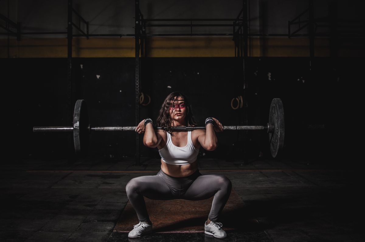 Mujer haciendo sentadilla con barra