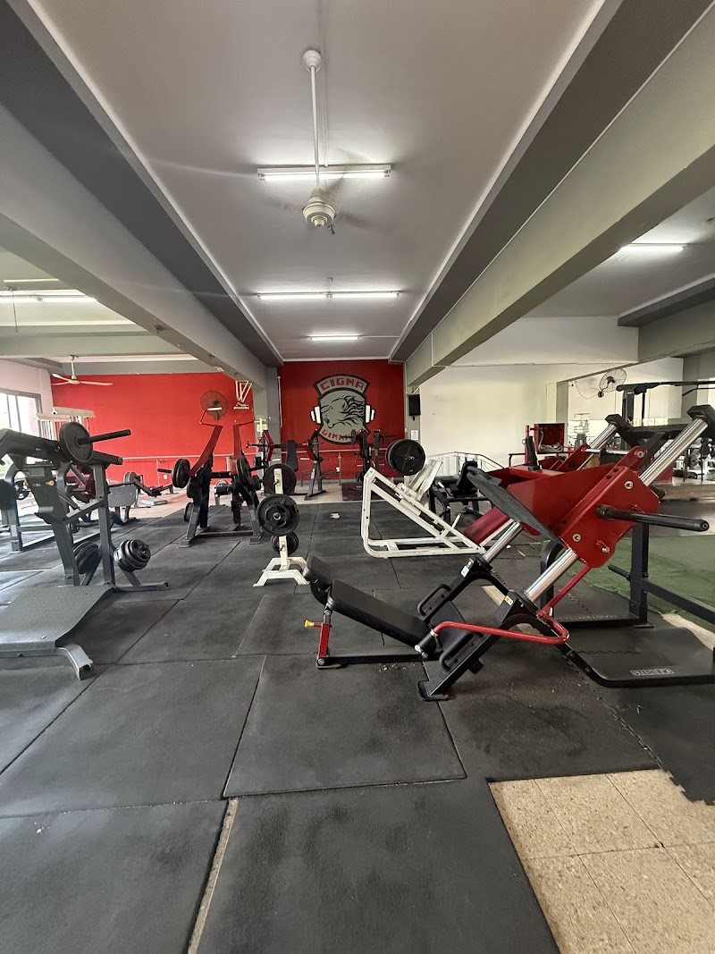 Sala de musculación de Gimnasio Cigma con el logo del gimnasio en la pared roja
