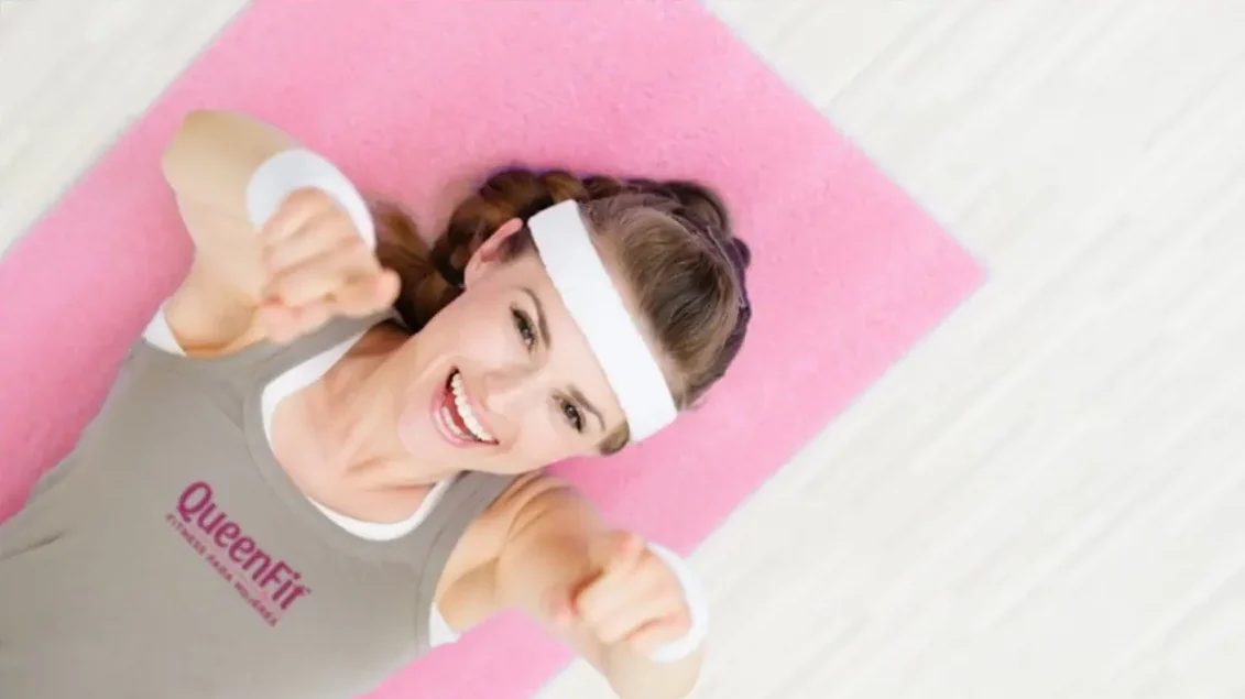Alumna de QueenFit sonriendo en el piso de entrenamiento