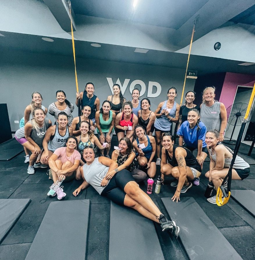 Grupo numeroso de alumnas de Wod Mendoza posando bajo el cartel del gimnasio